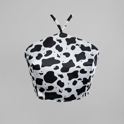 Black and white cow print top on a gray background