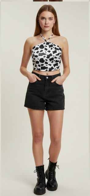 Woman wearing a cow print top and black shorts on a white background