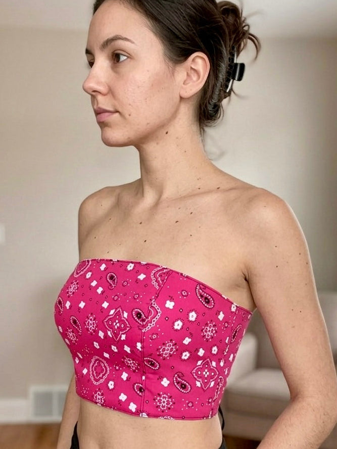 Woman wearing a pink bandeau top with a pattern in a room.
