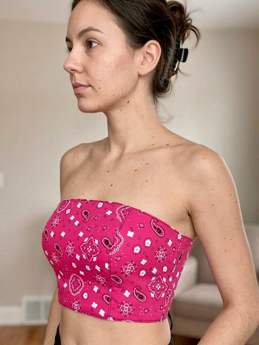 Woman wearing a pink bandeau top with a pattern in a room.